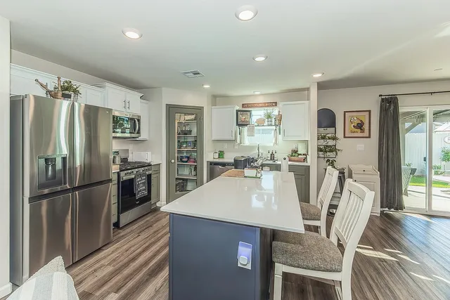 a kitchen with stainless steel appliances wooden floor dining table and chairs