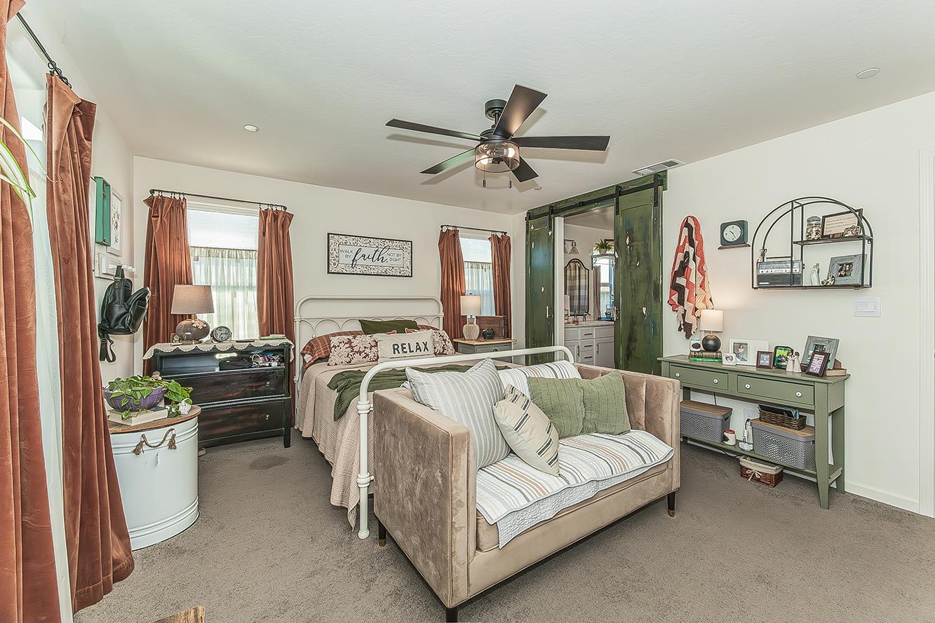 2161 Heidi Avenue Sanger, CA 93657 - Photo 17 of 43 a spacious bedroom with a bed a couch and a chandelier