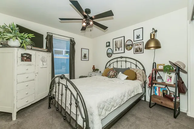 a bedroom with a bed a dresser and potted plants