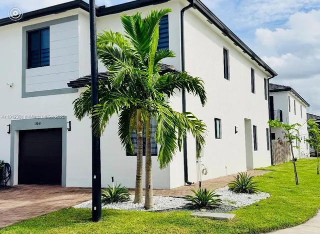 a palm tree sitting in front of a house with a yard