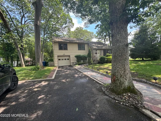 a view of a house with a small yard and a large tree