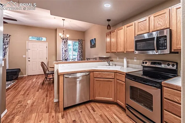 a kitchen with stainless steel appliances a stove a sink dishwasher and microwave oven with wooden floor