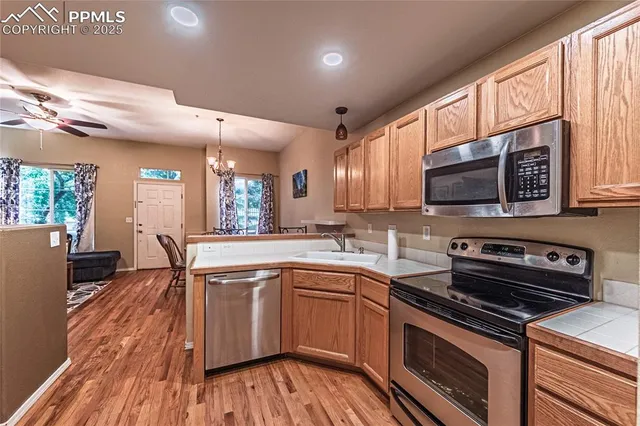 a kitchen with stainless steel appliances a stove a sink cabinets and a wooden floor