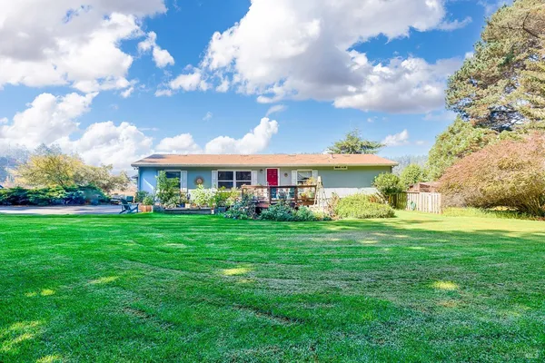 a view of a house with a yard and large trees