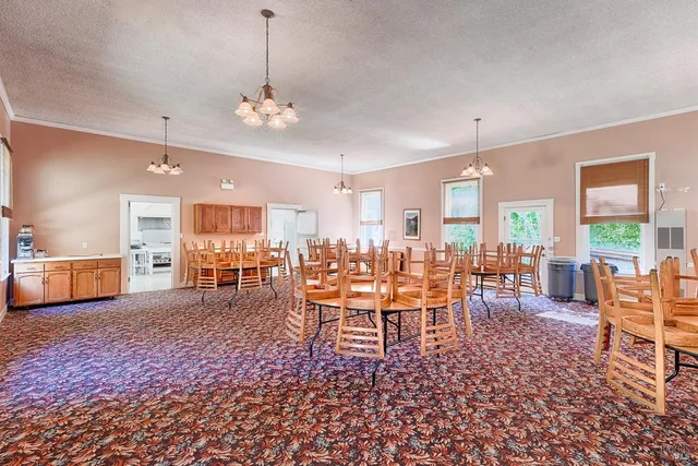 a kitchen with stainless steel appliances kitchen island granite countertop a table chairs in it and a window