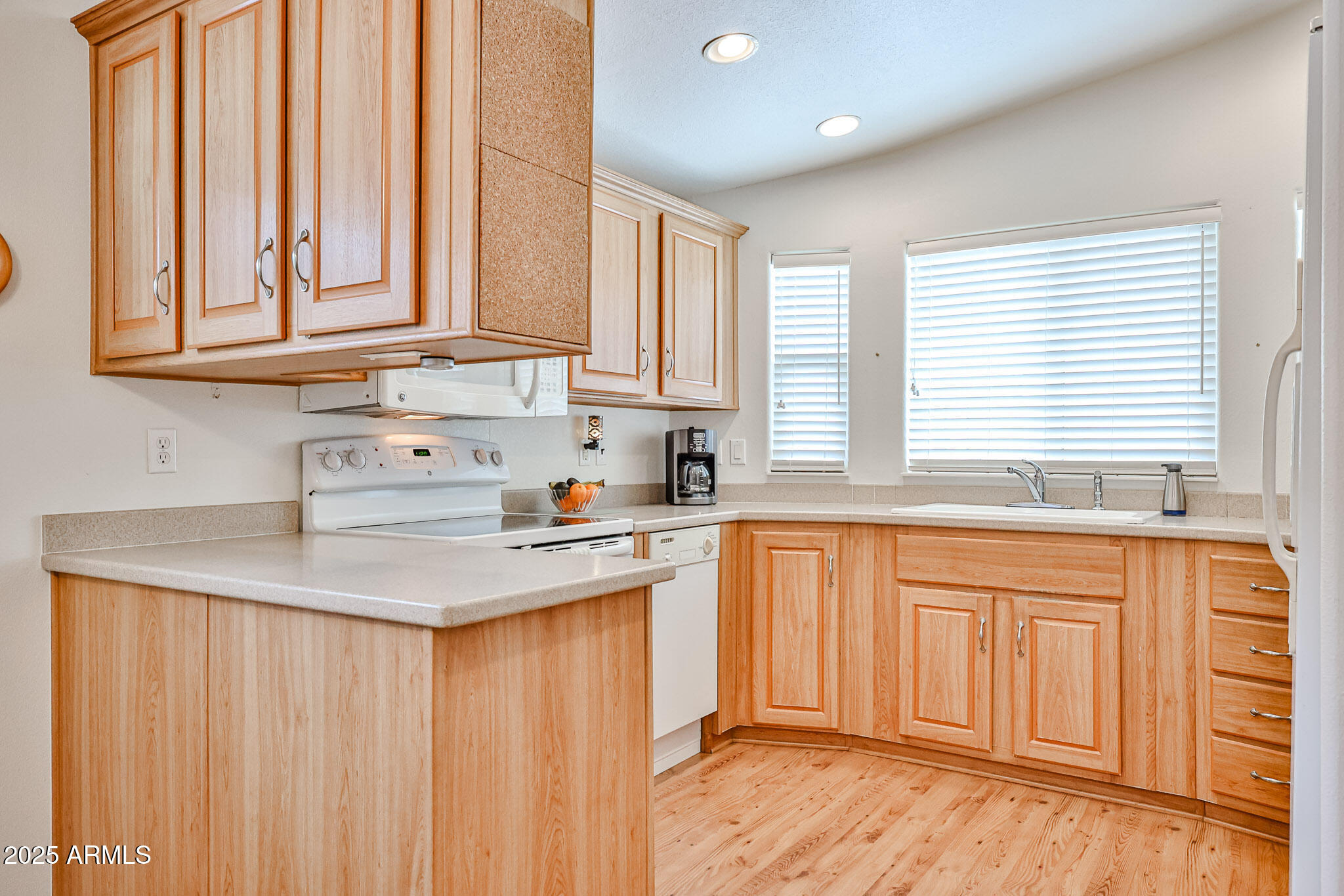 17200 West Bell Road, Unit 1185 Surprise, AZ 85374 - Photo 5 of 44 a kitchen with stainless steel appliances granite countertop a refrigerator a sink dishwasher and wooden cabinets with wooden floor