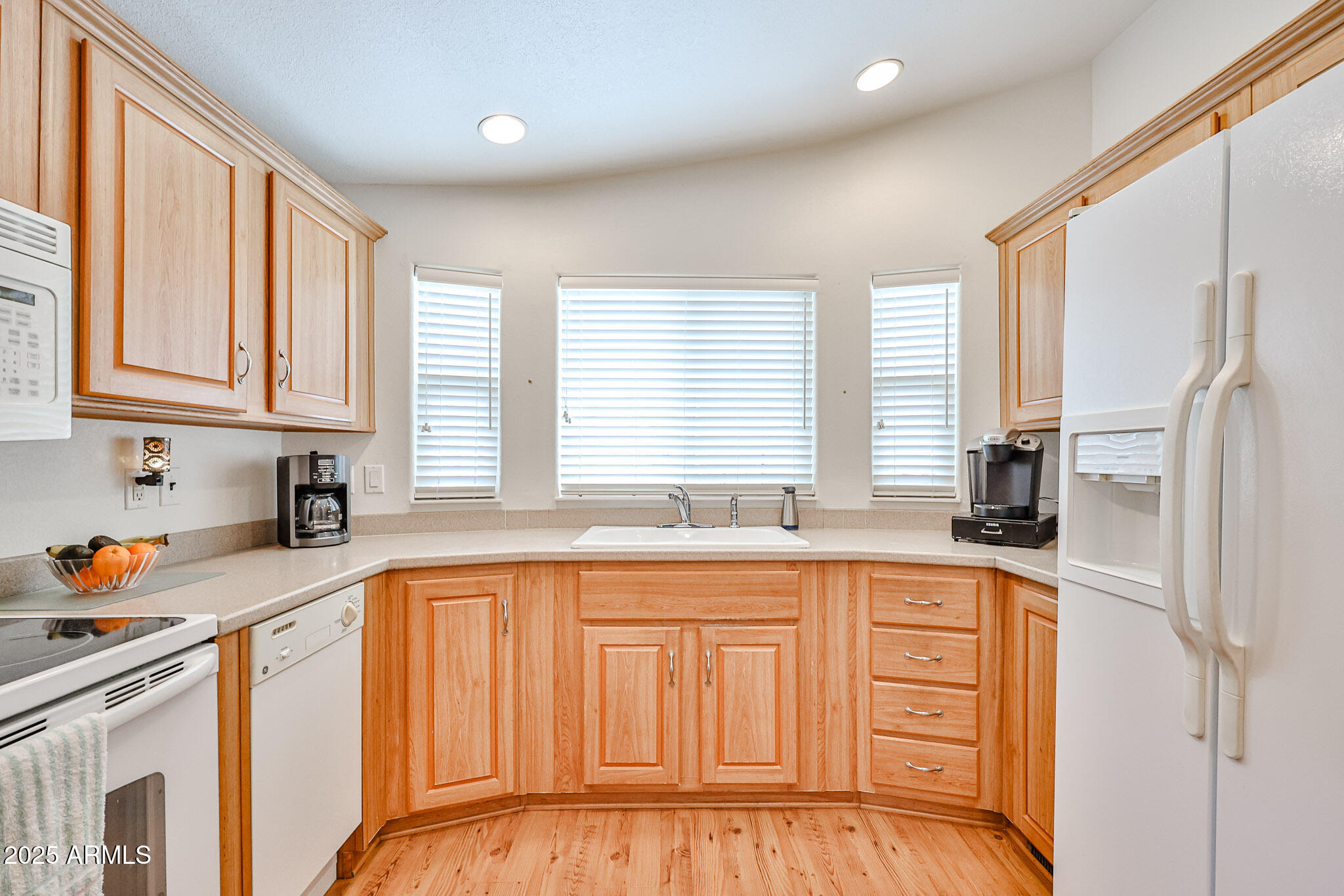 17200 West Bell Road, Unit 1185 Surprise, AZ 85374 - Photo 7 of 44 a kitchen with stainless steel appliances granite countertop a sink dishwasher a refrigerator with white cabinets and wooden floor