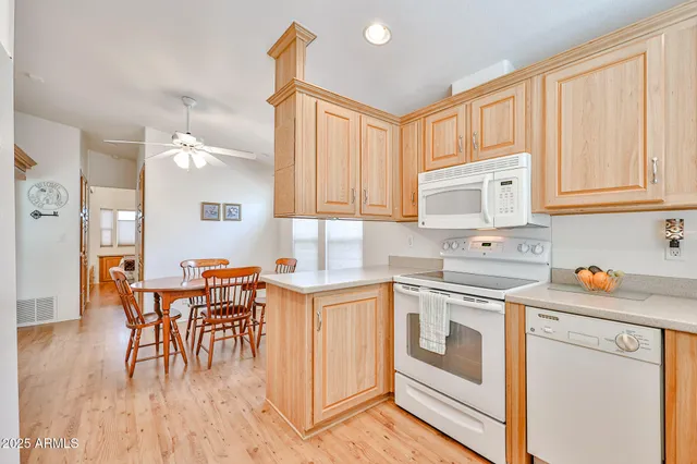 a kitchen with stainless steel appliances granite countertop a stove a sink dishwasher and white cabinets with wooden floor