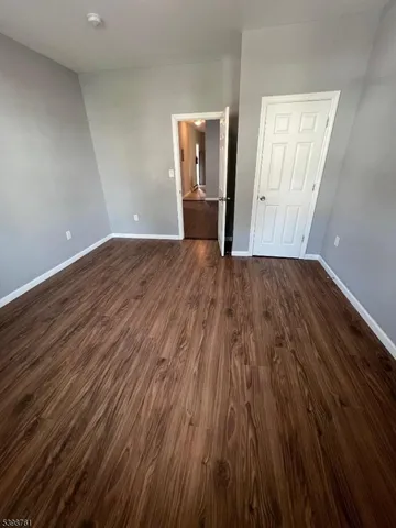 a view of an empty room with wooden floor and window