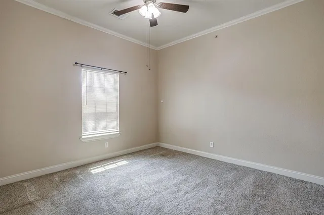 an empty room with a chandelier fan and windows