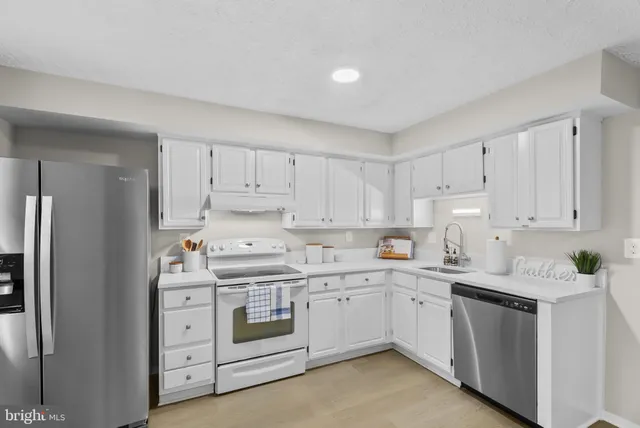 a kitchen with white cabinets sink and stainless steel appliances