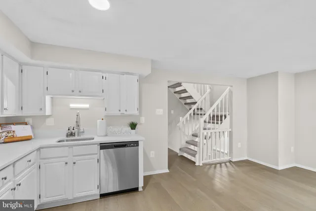 a kitchen with white cabinets and sink