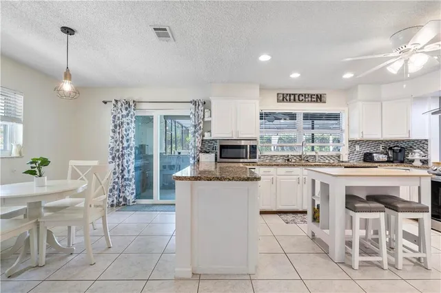 a view of a kitchen with kitchen island a counter top space a sink stainless steel appliances and cabinets