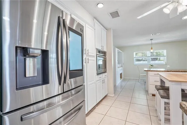 a kitchen with stainless steel appliances kitchen island granite countertop a refrigerator a stove a sink a dining table and chairs with wooden floor