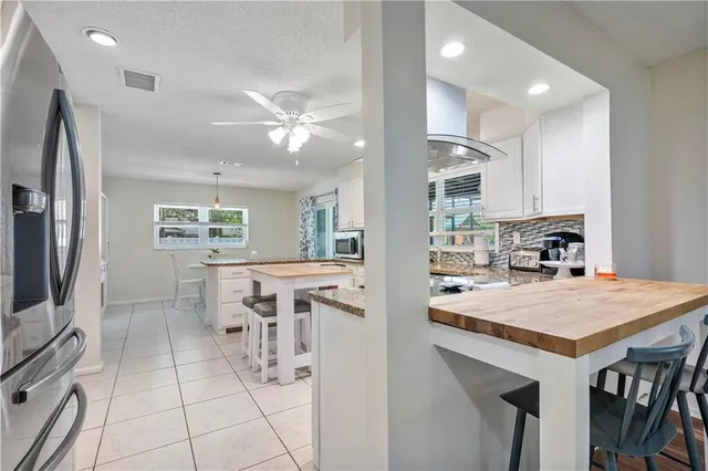 a kitchen with stainless steel appliances granite countertop table chairs sink refrigerator and microwave