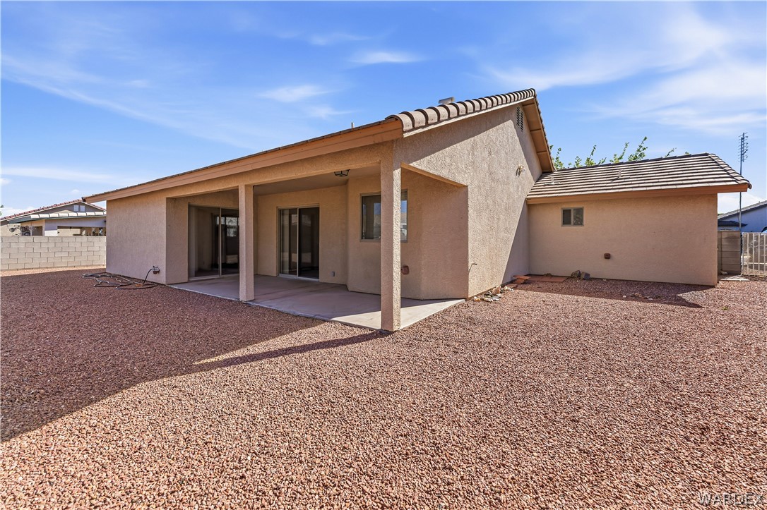 3973 Prairie View Drive Kingman, AZ 86409 - Photo 30 of 34 Rear exterior of the property featuring a covered patio, sliding glass doors, and a gravel yard