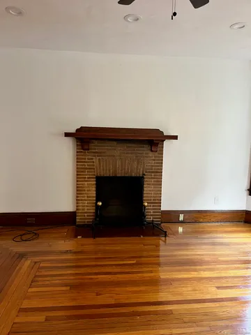 a view of a livingroom with wooden floor and a fireplace