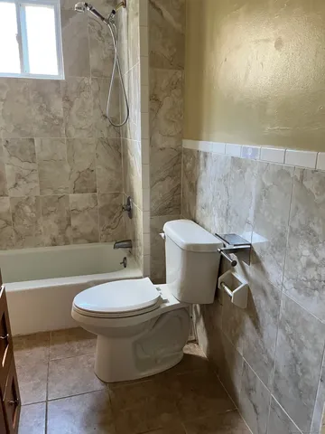 a white toilet sitting next to a bath tub and a shower