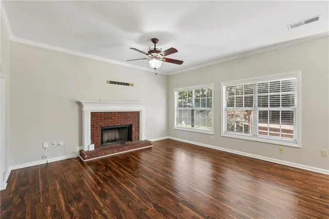 a view of an empty room with wooden floor fireplace and a window