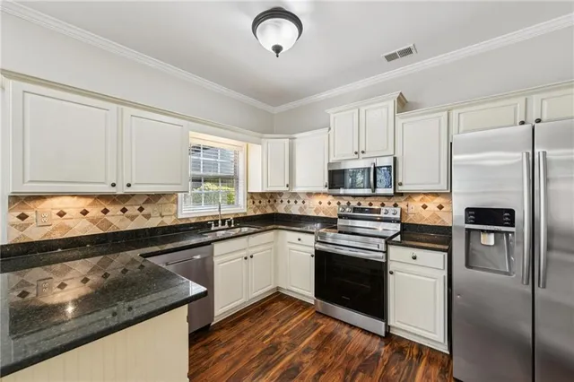 a white kitchen with granite countertop a stove and a sink