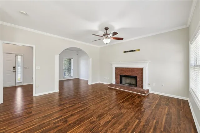 a view of an empty room with wooden floor fireplace and a window