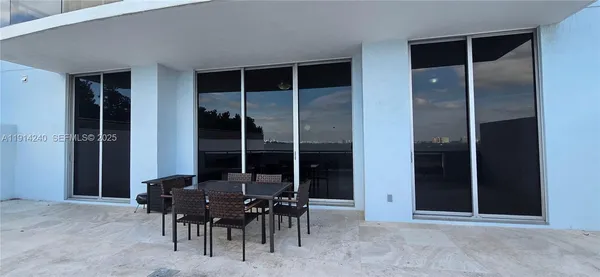 a view of a house that has a table and chairs in patio