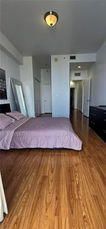 a large bedroom with wooden floor and natural light