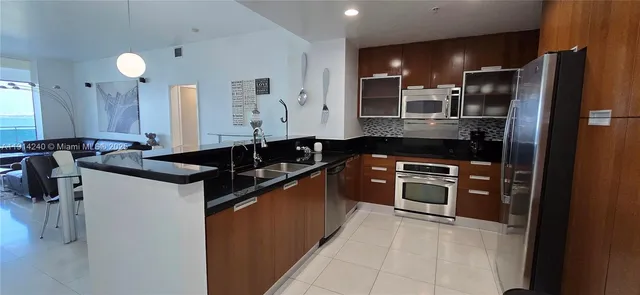 a kitchen with stainless steel appliances granite countertop a sink and a refrigerator