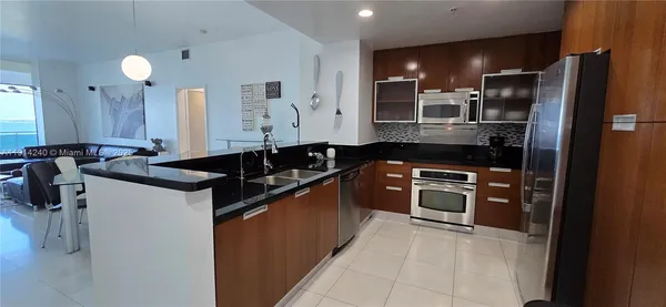 a kitchen with stainless steel appliances granite countertop a sink and a refrigerator