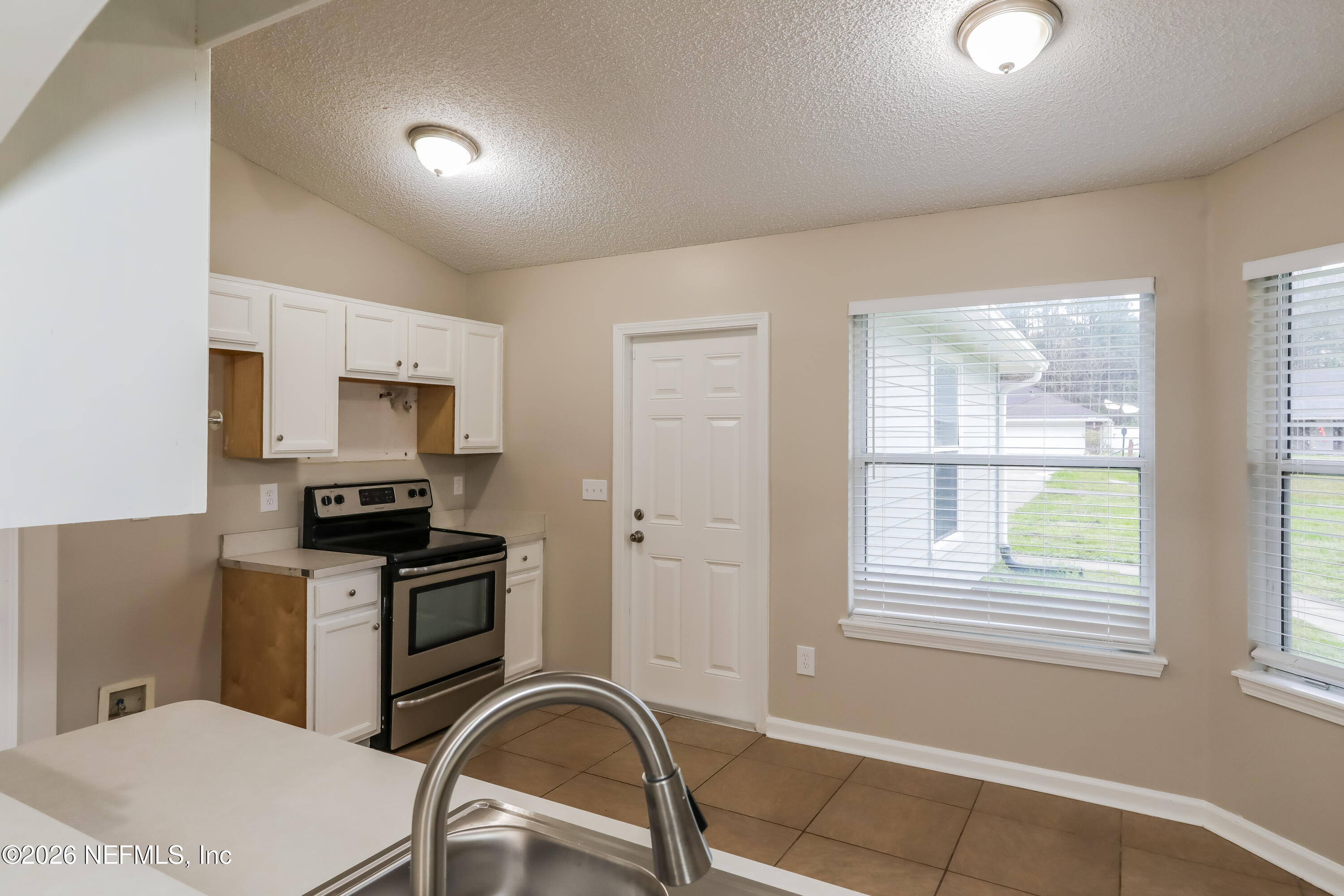 4088 Everett Avenue Middleburg, FL 32068 - Photo 6 of 16 a kitchen with stainless steel appliances a sink a stove a microwave a refrigerator a window and cabinets