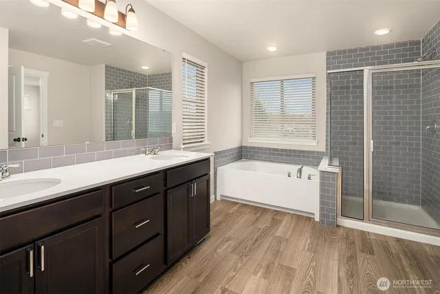 a bathroom with a double vanity sink large mirror and a bathtub