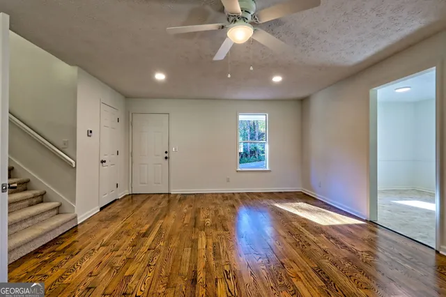a view of an empty room with wooden floor and a window