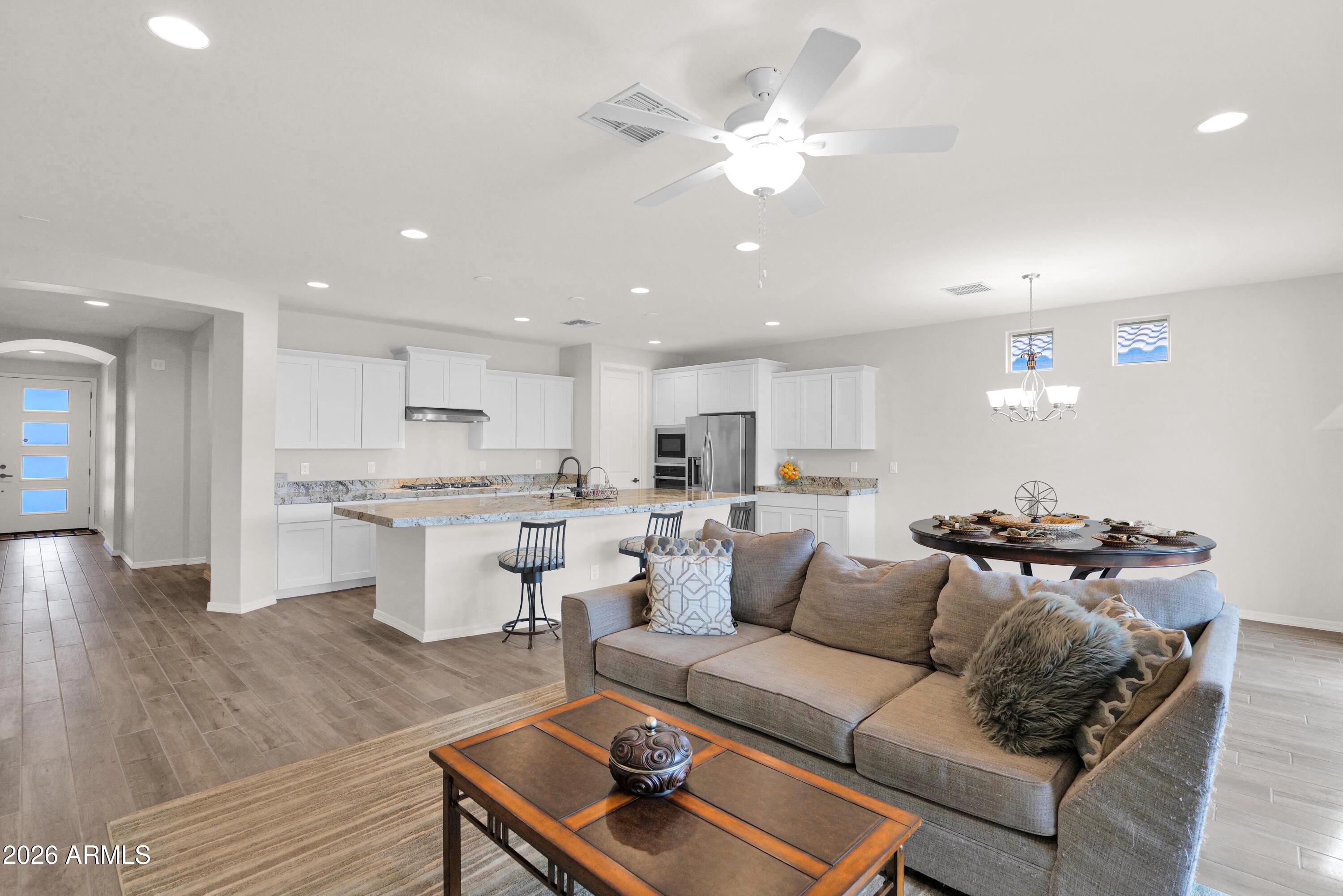 3461 West Oil Well Road San Tan Valley, AZ 85144 - Photo 8 of 25 a living room with white couches and kitchen view with wooden floor