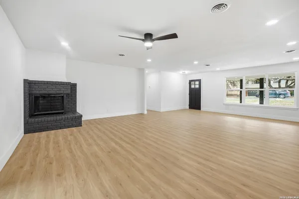 a view of an empty room with window and wooden floor