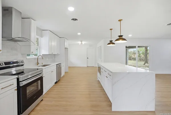 a large kitchen with stainless steel appliances a large counter top a stove a chimney a sink and a refrigerator