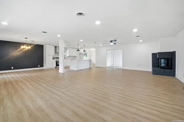 a view of an empty room with kitchen and a window