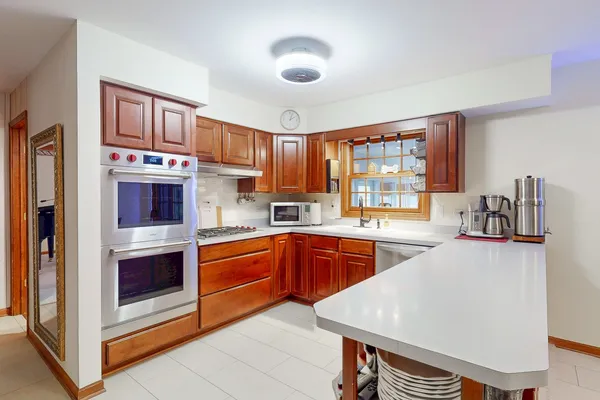 a kitchen with stainless steel appliances granite countertop a stove top oven a sink dishwasher and a refrigerator with wooden cabinets