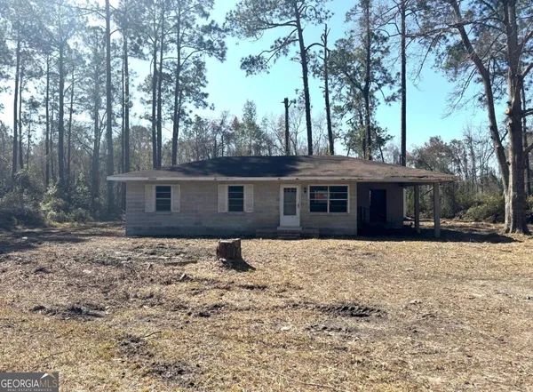 a front view of a house with a yard covered with trees