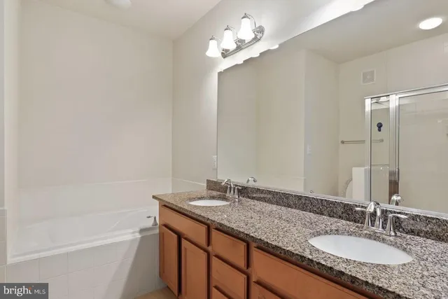 a bathroom with a granite countertop sink a mirror and a bathtub