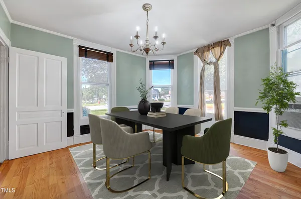 a dining room with chandelier and wooden floor