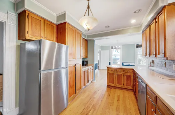 a kitchen with stainless steel appliances granite countertop a refrigerator a sink dishwasher a stove and white countertops with wooden floor