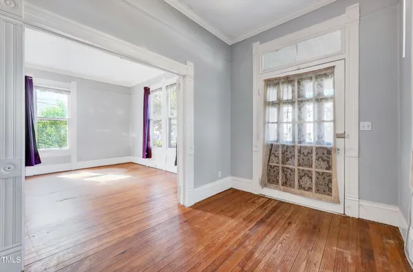 an empty room with wooden floor and windows
