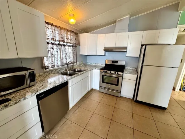 a kitchen with granite countertop a sink a counter top space cabinets and stainless steel appliances