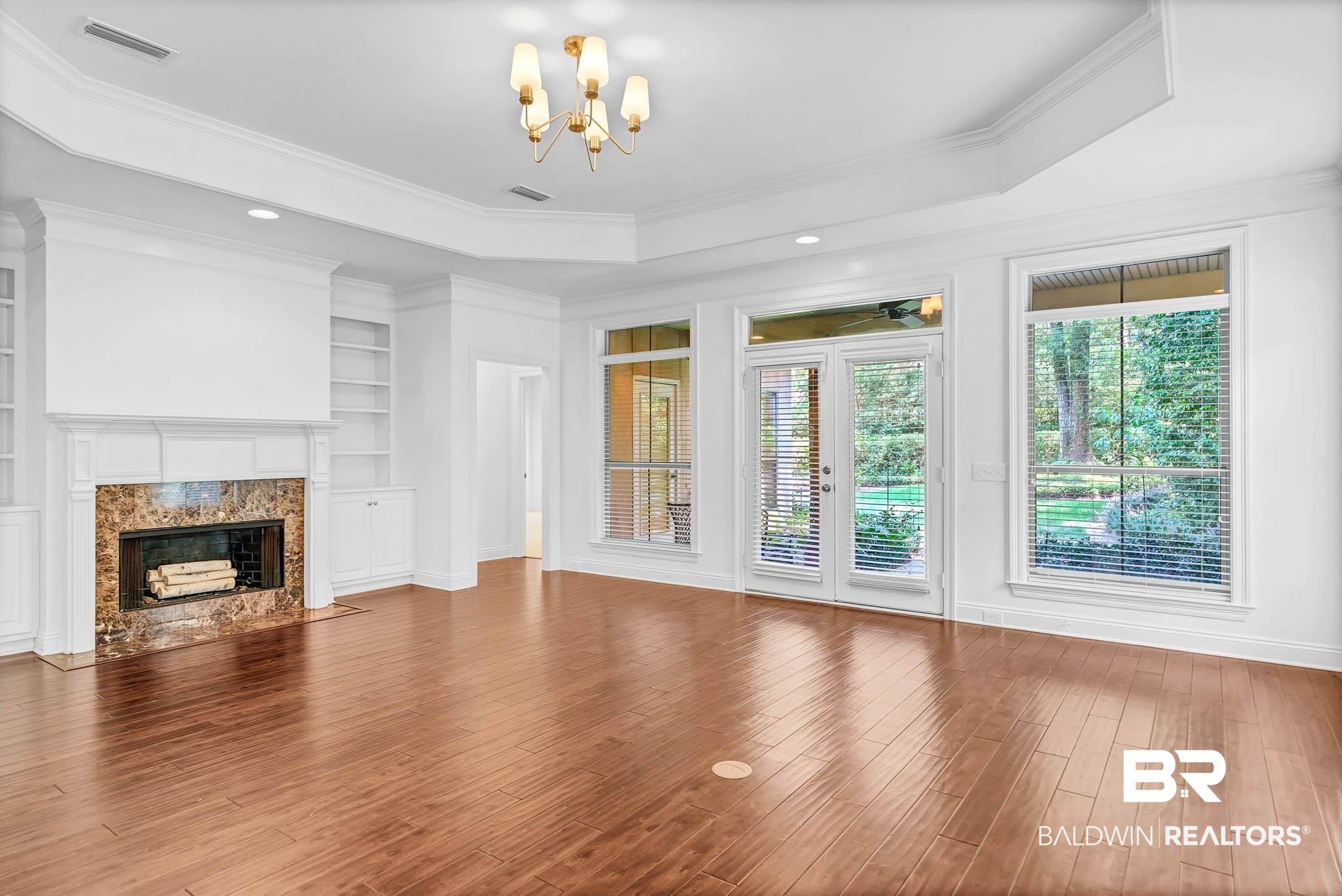 105 Cedar Pointe Fairhope, AL 36532 - Photo 9 of 38 Unfurnished living room featuring ornamental molding, plenty of natural light, a raised ceiling, a chandelier, and wood finished floors