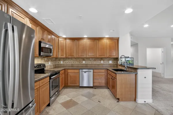 a kitchen with stainless steel appliances granite countertop a stove top oven a sink and dishwasher a refrigerator with wooden floor