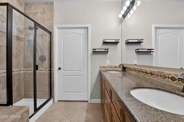 a bathroom with a granite countertop sink a mirror and shower