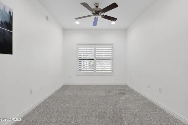an empty room with a window and a fan
