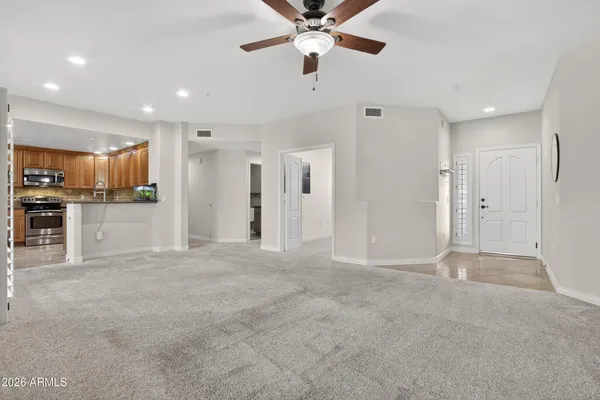a view of a livingroom with a kitchen space stainless steel appliances and a chandelier