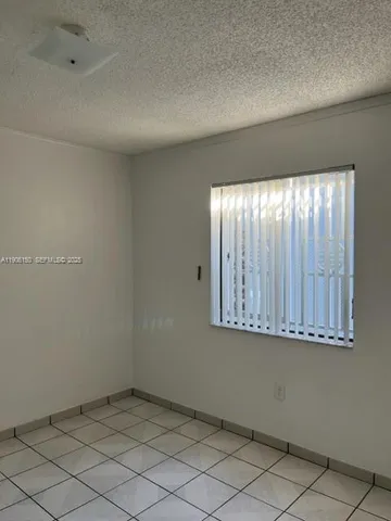 an empty room with wooden floor and fan