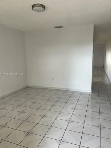 a view of hallway with a white cabinet and a refrigerator